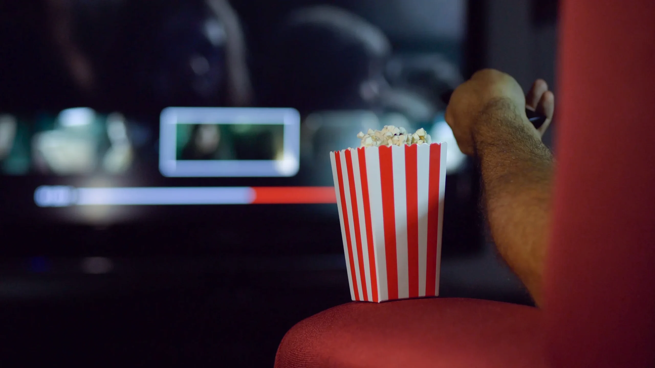 A man chooses scenes from the tv series while eating popcorn.