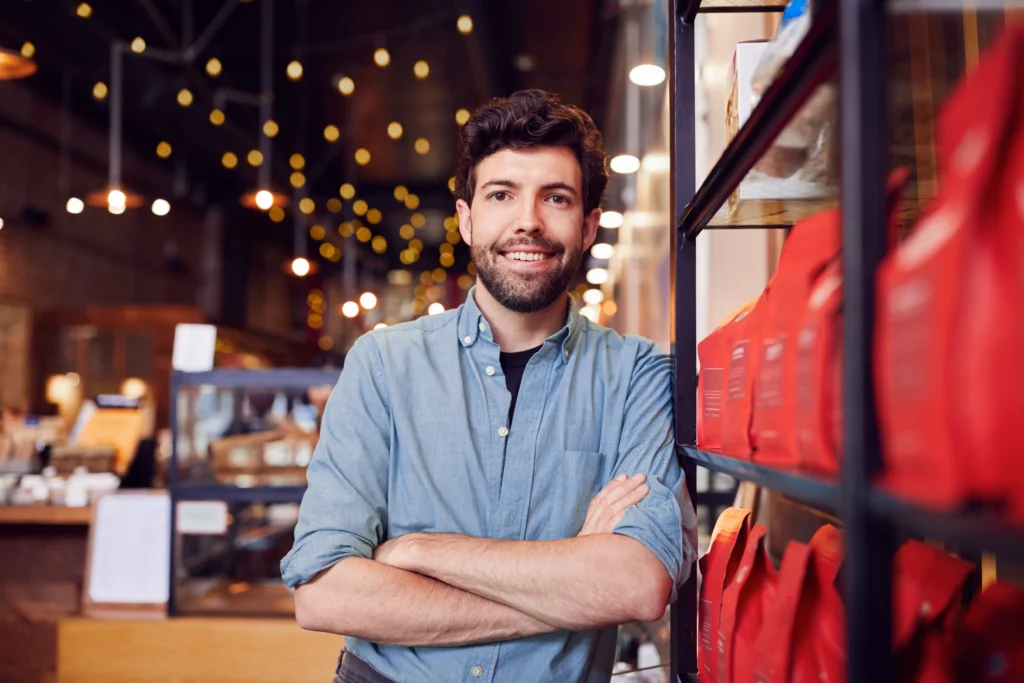 portrait-of-male-coffee-shop-owner-standing-by-cou-